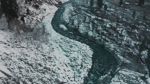 Aerial view of a river in between the mountains covered with snow Stock Footage 172472029