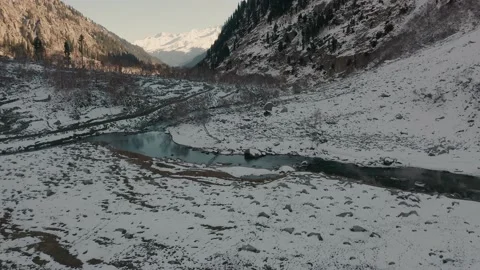 Aerial view of a river in between the mountains covered with snow Stock Footage 172473463