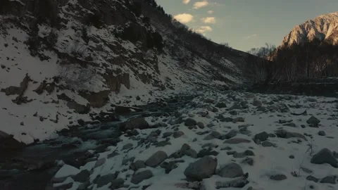 Aerial view of a river in between the mountains covered with snow Stock Footage 172523507