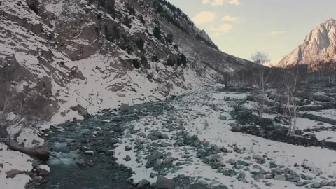 Aerial view of a river in between the mountains covered with snow Stock Footage 172538020