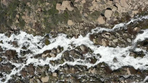 Aerial view of a river between rocks on a wet dirt road, the water flows Stock Footage 171597878