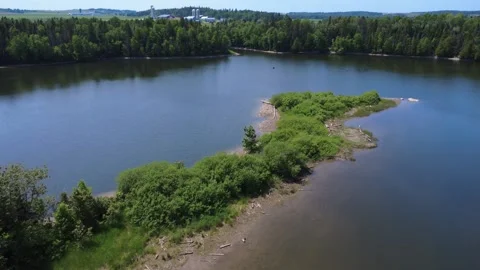 Aerial view of a river bordered by forest with a farm and hydroelectric dam. Stock Footage 313635702