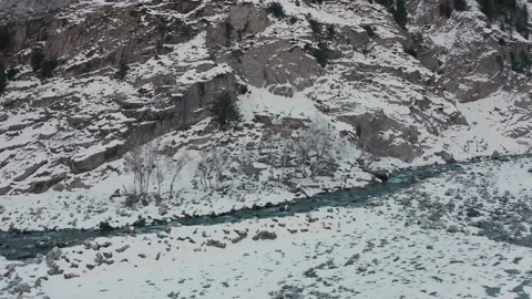 Aerial view of a river flowing in between the mountains covered with snow Stock Footage 172398034