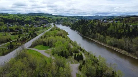 Aerial view of a river flowing parallel to the road in a lush green valley. Stock Footage 304300201