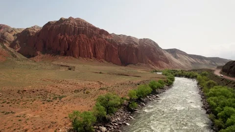Aerial view of river flowing through a valley with red rock formations in Stock Footage 288565688