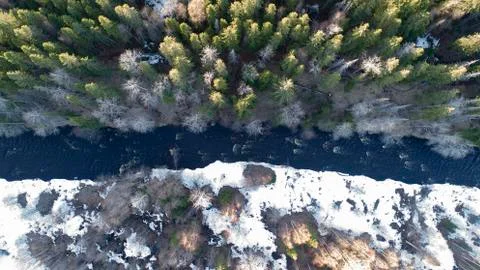 Aerial view of a river in the forest with snow along the banks. Stock Photos