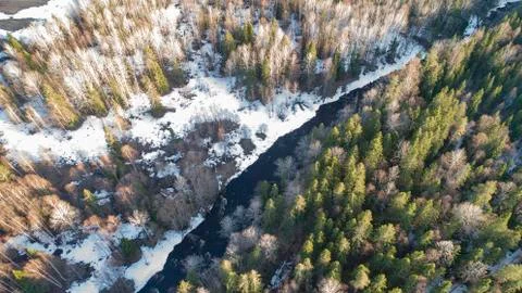 Aerial view of a river in the forest with snow along the banks. Stock Photos