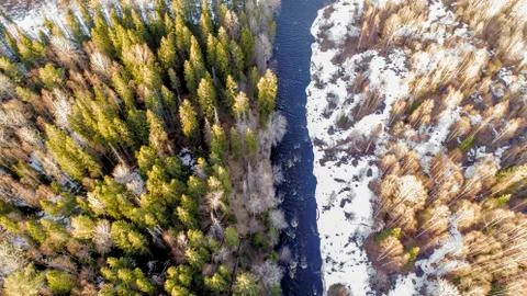 Aerial view of a river in the forest with snow along the banks. Stock Photos