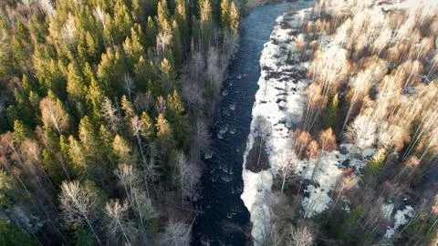 Aerial view of a river in the forest with snow along the banks. Stock Photos