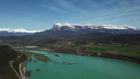 Aerial view of a river in Huesca overlooking fields and snowy mountains Stock Footage 304237334