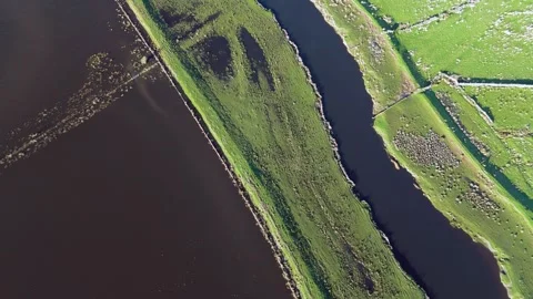Aerial view of a river meandering through vibrant green fields during a flood. Stock Footage 296847091