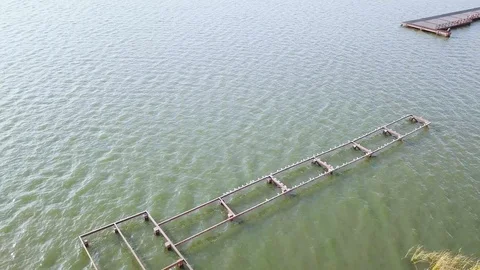 Aerial view of the river with small ripples and the pier under the summer sun Видео 129188758