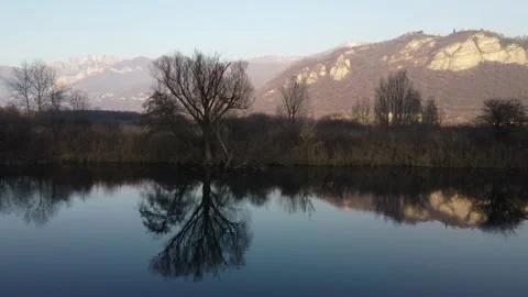 Aerial view of a river at sunset with a flying duck and mountains Stock Footage 166527594