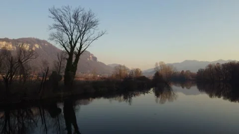 Aerial view of a river at sunset with a flying duck and mountains Video stock 166527616