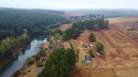 Aerial view of a river surrounded by dense forest and houses on a cloudy day Stock Footage 308979090
