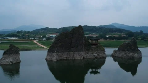 Aerial view of a river with three rocks in the center and pavilion on top 動画素材 244484235