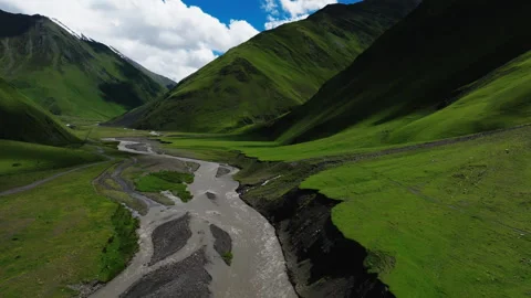 Aerial View of River Winding Through a Lush Green Valley with Mountain Roads and Stock Footage 268451369