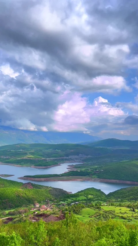 Aerial View of River Winding Through Lush Green Mountains Under Dramatic Sky Stock Footage 310210096