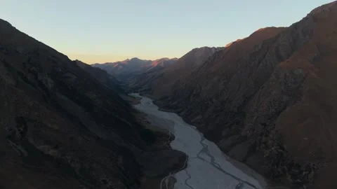 Aerial view of river winding through mountains at dawn, camera pans smoothly Video stock 321448328