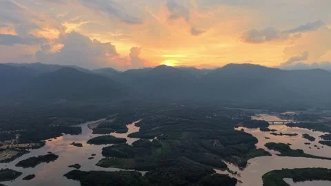 Aerial view of river winding through lush forest landscape under sunset sky Video stock 339857723