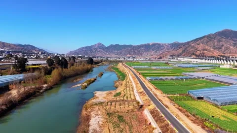Aerial View of a River Winding Through an Agricultural Valley with Greenhouses 動画素材 346928022