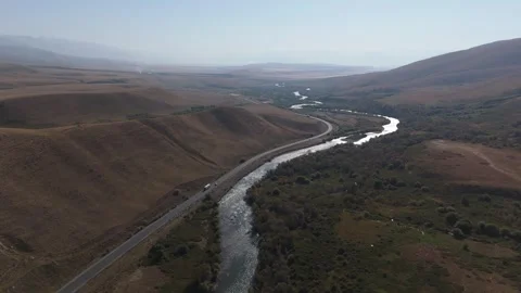 Aerial view of a river winding through a valley beside a highway, Kyrgyzstan Stock Footage 347242370