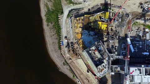 Aerial View of Riverside Construction Site With Heavy Machinery and Cranes in Stock Footage 342052468
