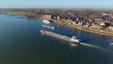 Aerial view of a riverside town featuring two cargo ships, a stone embankment Stock-Footage 329076385