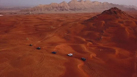 Aerial view of off road 4x4 suv vehicles driving across expansive red sand .. Stock Footage 337172064