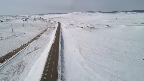 Aerial view on a road between the white snowy hills with cars driving on it Video stock 154129023