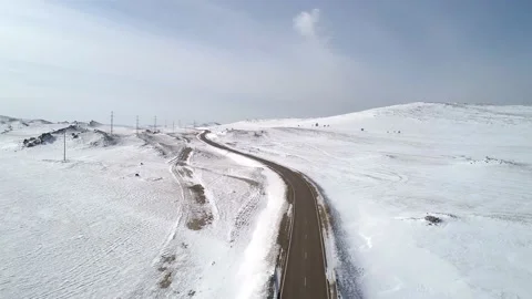 Aerial view on a road between the white snowy hills against the blue sky. Stock Footage 154130436