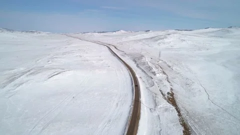 Aerial view on a road between the white snowy hills with a car driving on it Stock-Footage 154130506