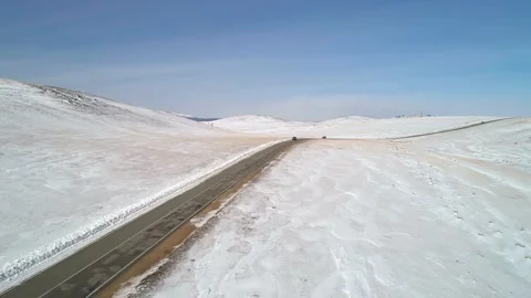 Aerial view on a road between the white snowy hills with cars driving on it Stock Footage 154134542
