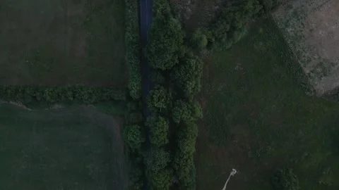 An aerial view of a road bordered by trees and fields. A large, light-color.. Stock Footage 340473457