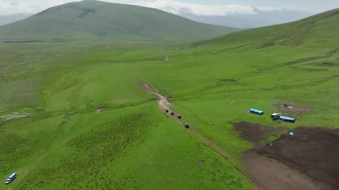Aerial view of off-road buggies driving through scenic green mountains Stock Footage 341097074