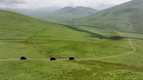Aerial view of off-road buggies driving through scenic green mountains Stock Footage 341097107