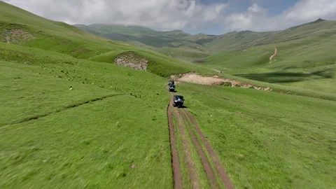 Aerial view of off-road buggies driving through scenic green mountains Stock Footage 341097177