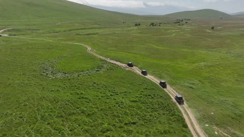 Aerial view of off-road buggies driving through scenic green mountains Stock Footage 341099896