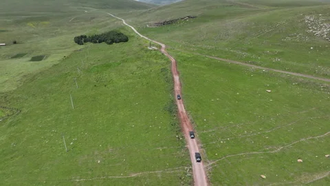 Aerial view of off-road buggies driving through scenic green mountains Stock Footage 341100797