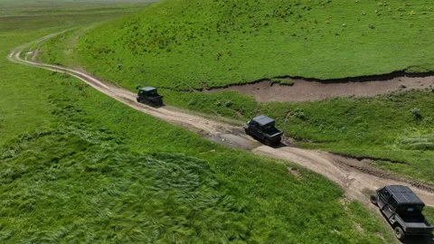 Aerial view of off-road buggies driving through scenic green mountains Stock Footage 341101129