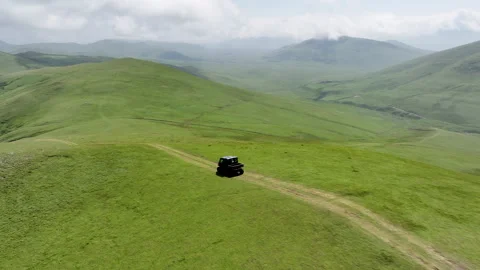 Aerial view of off-road buggies driving through scenic green mountains Stock Footage 341101825