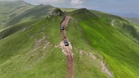 Aerial view of off-road buggies driving through scenic green mountains Stock Footage 341101957