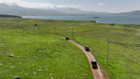 Aerial view of off-road buggies driving through scenic green mountains Stock Footage 341102054