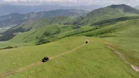 Aerial view of off-road buggies driving through scenic green mountains Stock Footage 341102236