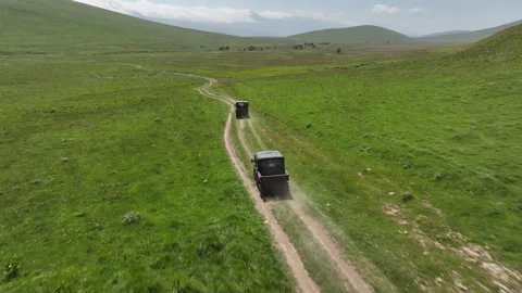Aerial view of off-road buggies driving through scenic green mountains Stock Footage 341102671