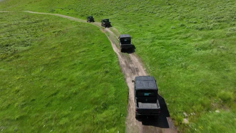 Aerial view of off-road buggies driving through scenic green mountains Stock Footage 341103621