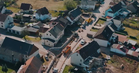 Aerial view of road construction site with excavator and truck in village Stockbeeldmateriaal 329560836