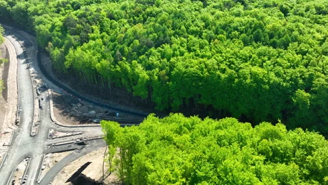 Aerial View Of Road Construction Site Next To Lush Green Forest Stock Footage 335482943