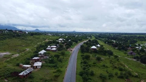 Aerial view of a road cutting through a rural landscape with houses and green Stock Footage 313315537