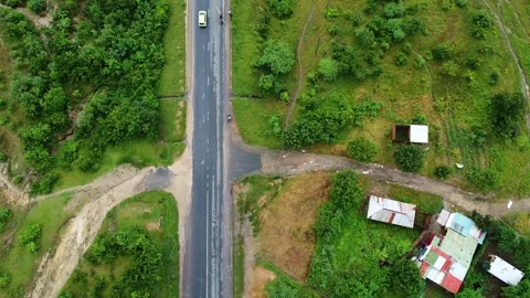 Aerial view of a road cutting through lush green landscape with a white van Stock Footage 313315898